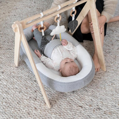 Baby playing with the hanging toys on the Doomoo Cocoon Arch.